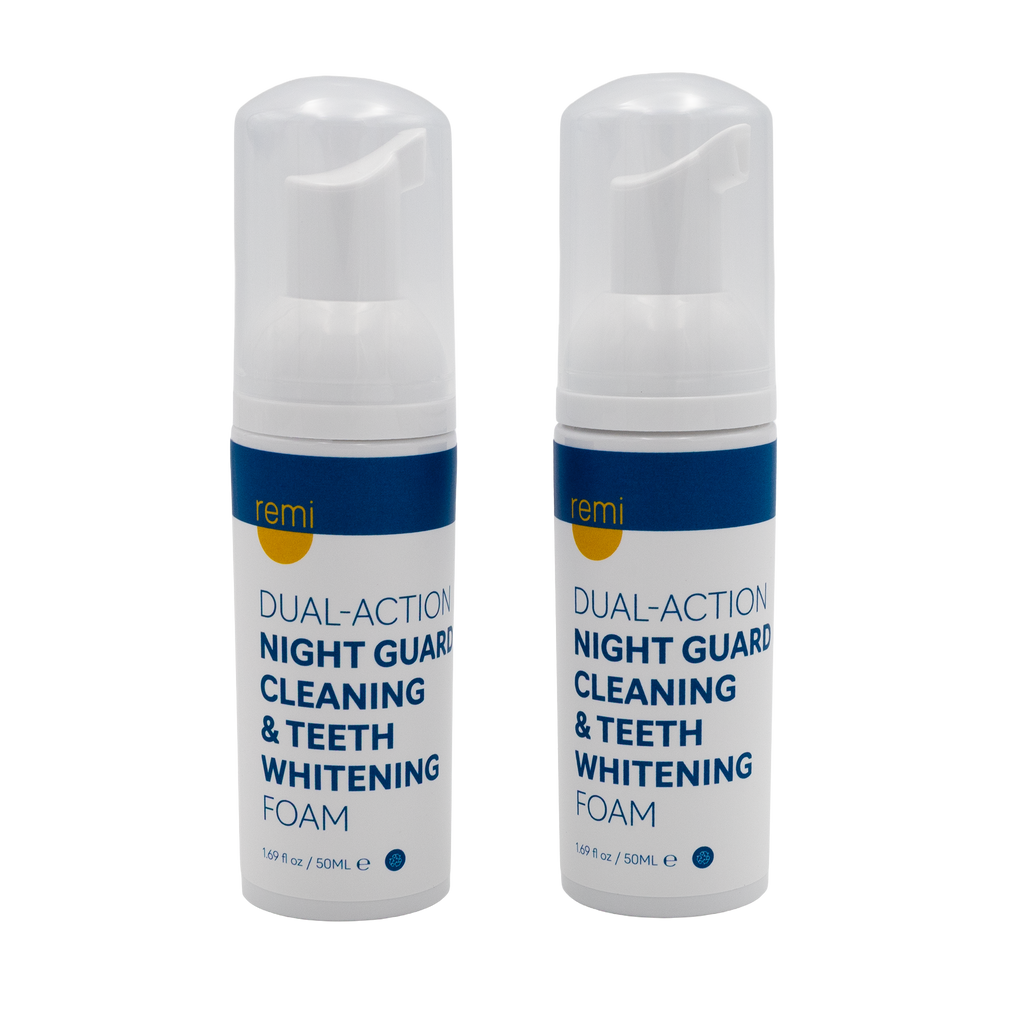 Two bottles of Remi Dual-Action Night Guard Cleaning & Teeth Whitening Foam, perfect for at-home dental care and teeth grinding protection, stand side by side with white bodies, blue and yellow labels, and clear pump caps on a white background.