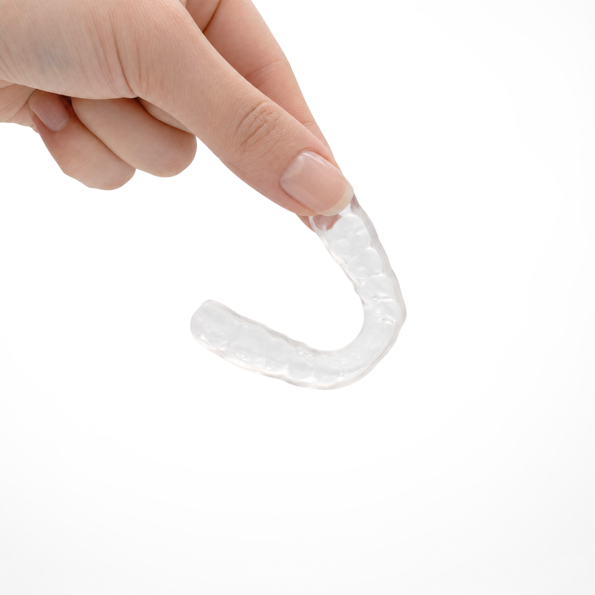 Hand holding a clear Remi custom night guard, thin and lightweight