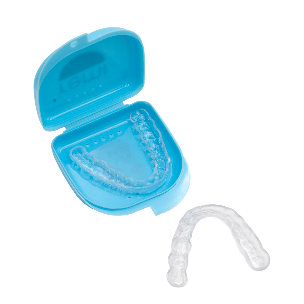 A clear dental aligner case, with one aligner inside and one placed outside, is shown on a white background. The blue open case displays transparent orthodontic aligners, similar in appearance to a custom night guard used to prevent teeth grinding.