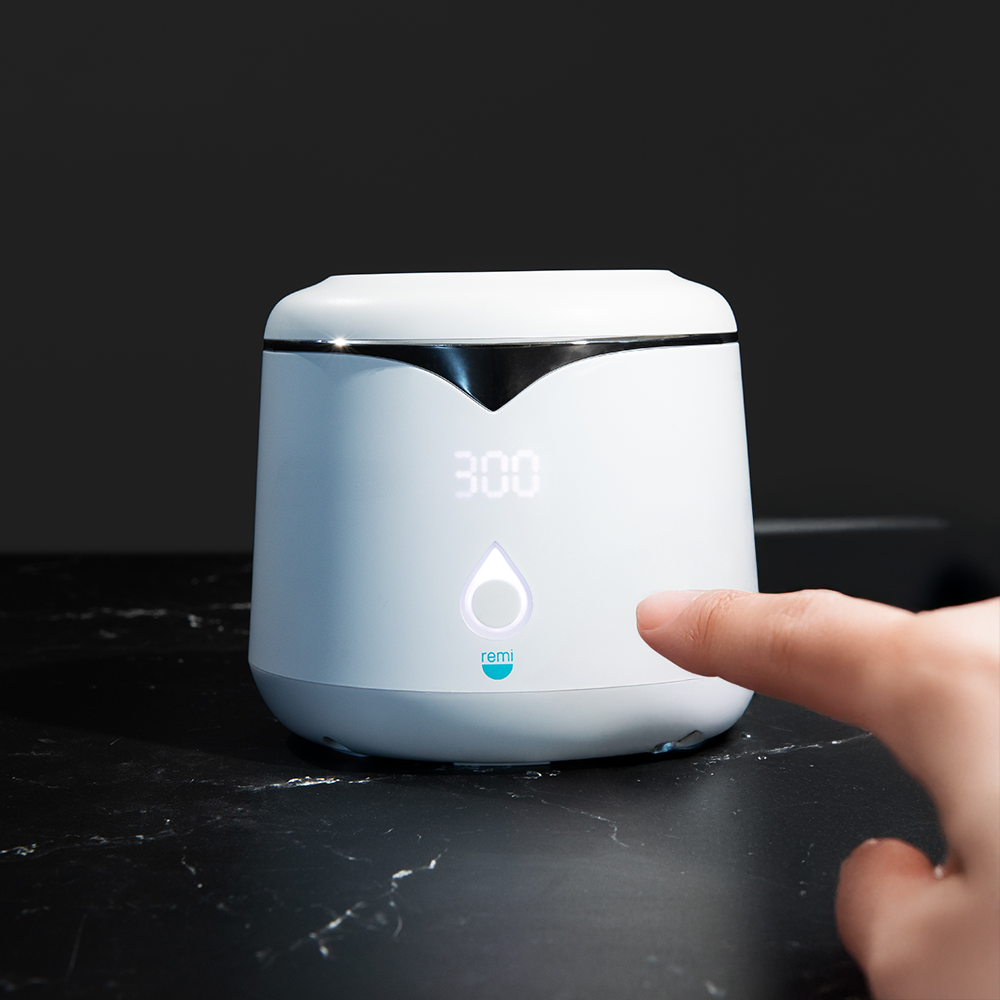 A hand is about to press a lit button on a white, modern smart device displaying 300 on its digital screen, set against a dark background.